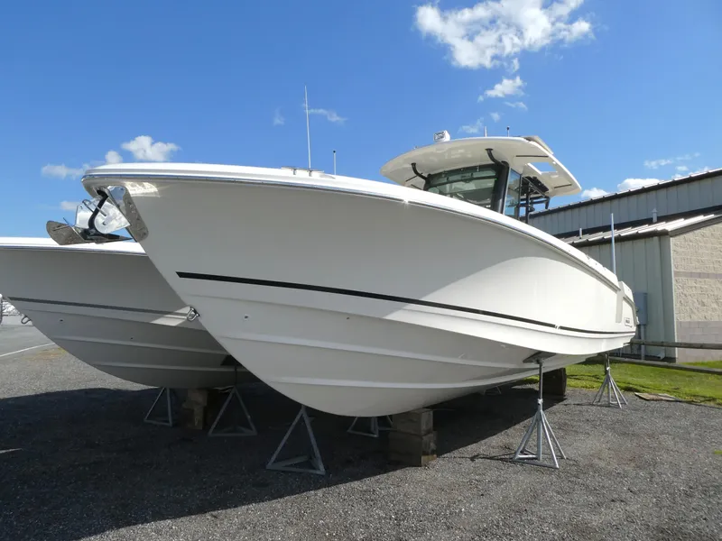 Slide: The Image of 2025 Boston Whaler 330 Outrage boat on stands, clear sky background. - 3