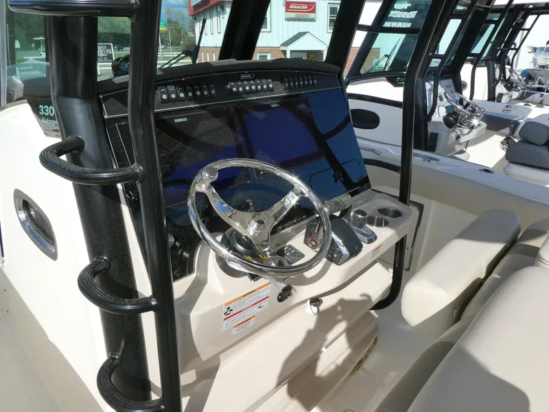 Slide: The Image of 2025 Boston Whaler 330 Outrage helm with modern controls and steering wheel. - 8
