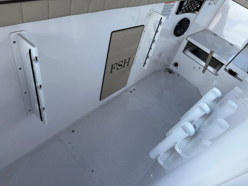 Slide: The Image of 2025 Yamaha Boats 222 FSH Sport E interior with rod holders and storage. - 13