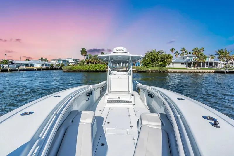 Slide: The Image of 2021 Yellowfin 36 Offshore boat on water at sunset, with coastal homes in background. - 12