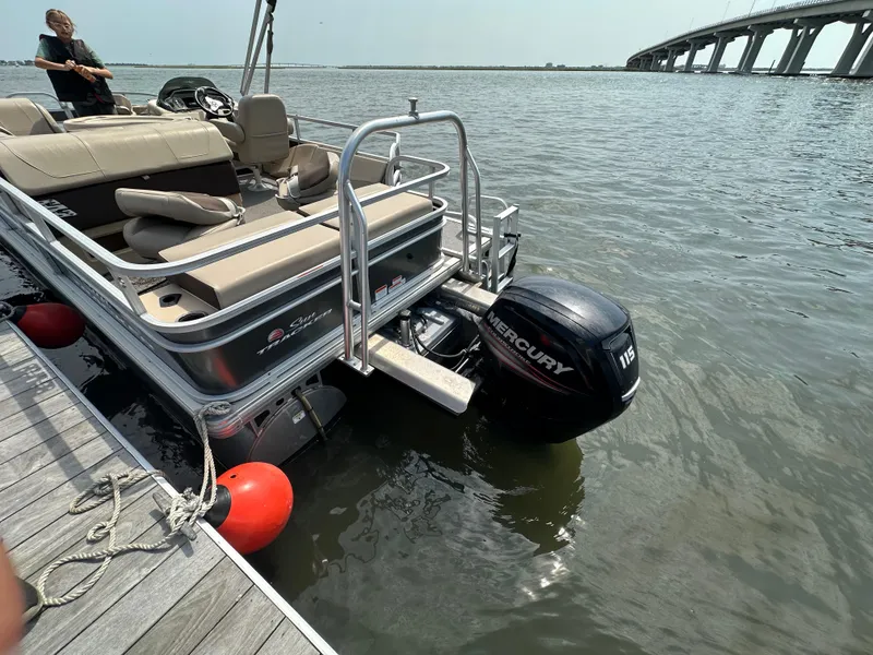 Slide: The Image of 2018 Sun Tracker Fishing Barge 22 docked, featuring Mercury 115 outboard motor, near a bridge. - 13