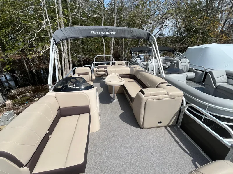 Slide: The Image of 2018 Sun Tracker Fishing Barge 22 pontoon boat with spacious seating and canopy, docked near trees. - 18