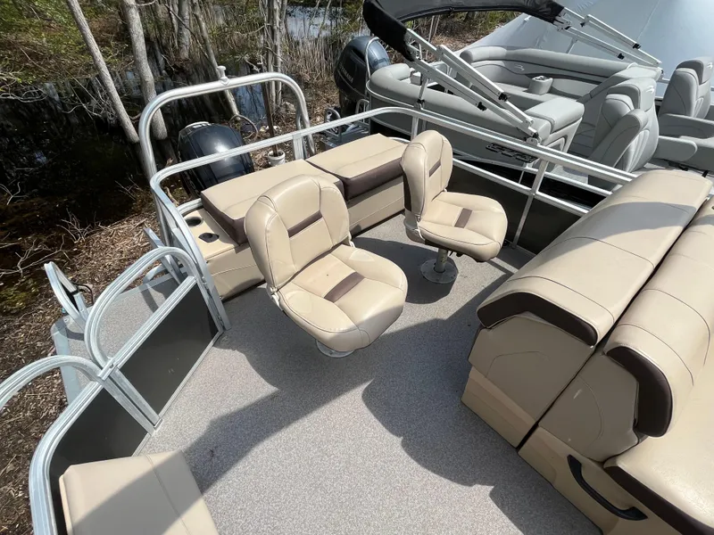 Slide: The Image of 2018 Sun Tracker Fishing Barge 22 interior with beige seating and fishing chairs. - 20