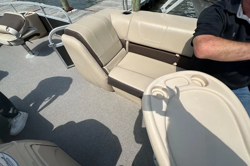 Slide: The Image of 2018 Sun Tracker Fishing Barge 22 interior with beige seating and table on a sunny day. - 23
