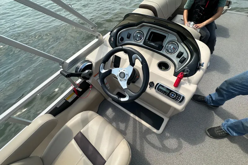 Slide: The Image of 2018 Sun Tracker Fishing Barge 22 dashboard with steering wheel and controls on water. - 24