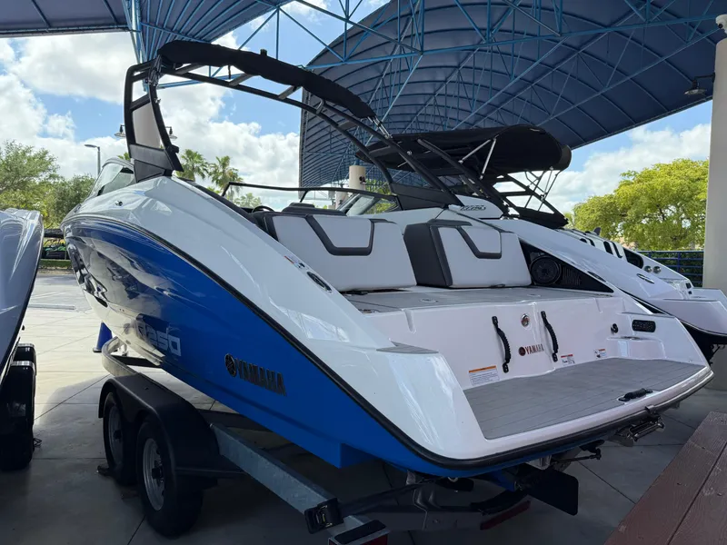 Slide: The Image of 2025 Yamaha Boats AR250, sleek design, blue and white, on trailer under canopy. - 4