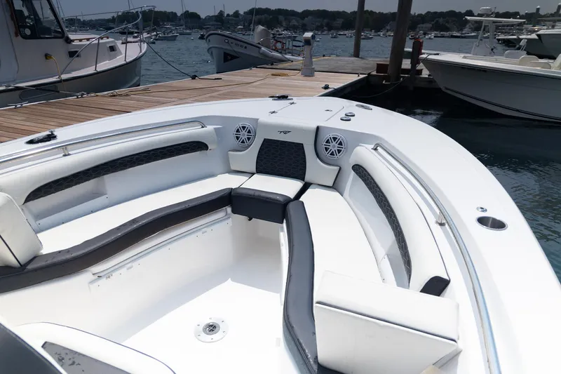 Slide: The Image of 2025 Tidewater 230 LXF boat interior with cushioned seating at a marina dock. - 11