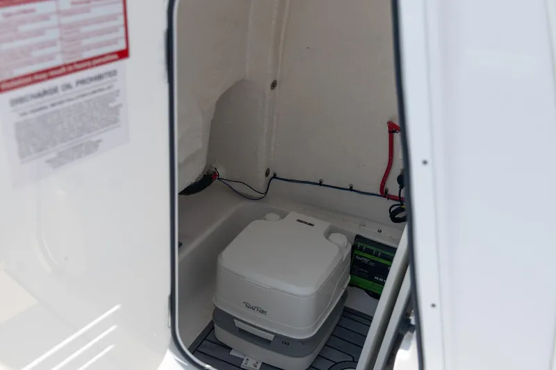 Slide: The Image of Interior of 2025 Tidewater 230 LXF boat featuring a portable toilet and battery compartment. - 24