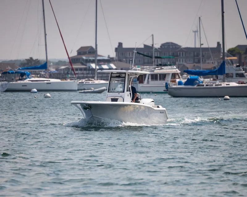Slide: The Image of 2025 Tidewater 230 LXF boat cruising in a marina with sailboats in the background. - 26