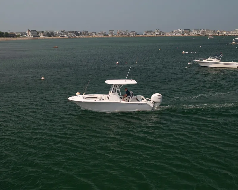 Slide: The Image of 2025 Tidewater 230 LXF boat cruising on calm waters near a coastal town. - 31