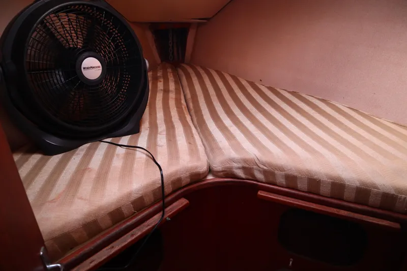 Slide: The Image of 1997 Hunter 37 boat cabin with striped bedding and a fan. - 17