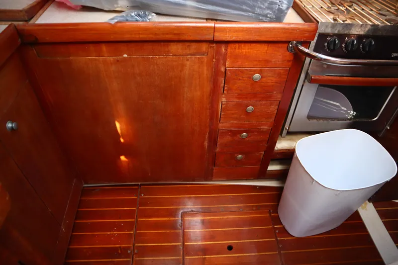 Slide: The Image of 1997 Hunter 37 yacht kitchen with wooden cabinets, stove, and trash bin. - 21