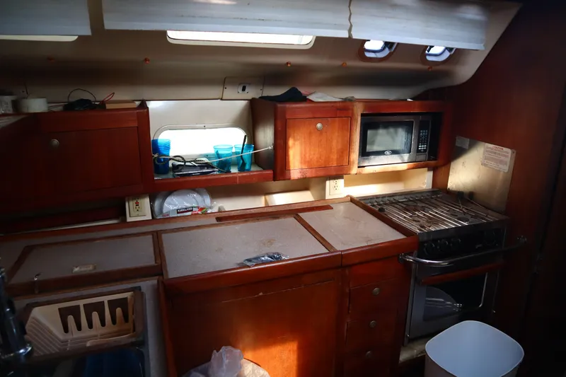 Slide: The Image of 1997 Hunter 37 yacht kitchen with wooden cabinets, microwave, and stove. - 22