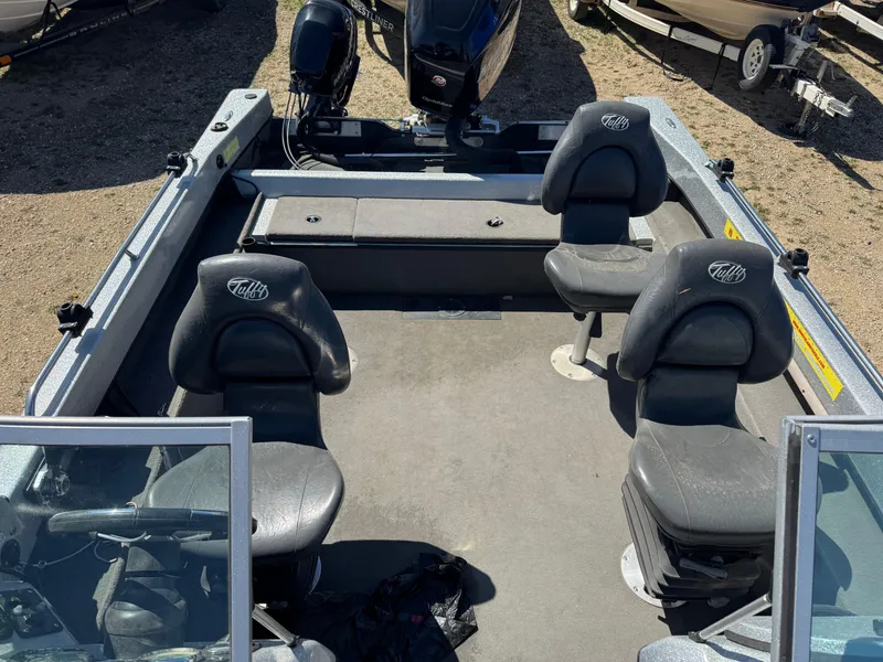 Slide: The Image of 2016 Tuffy Osprey 2100 boat interior with seating and motor, parked on gravel. - 18