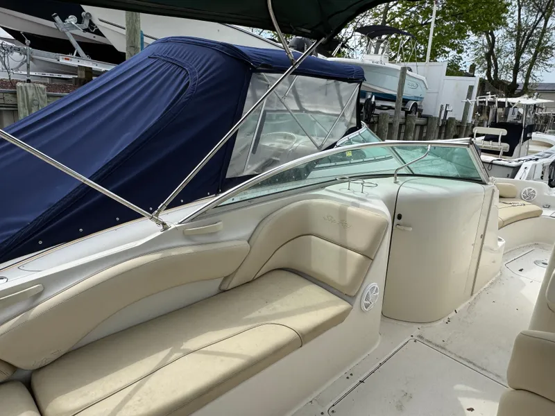 Slide: The Image of 2001 Sea Ray 240 Sundeck boat with beige seating and glass windshield at a marina. - 11