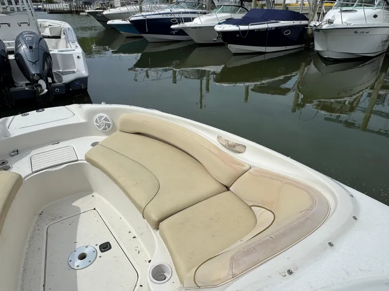 Slide: The Image of 2001 Sea Ray 240 Sundeck boat with beige seating, docked among other boats. - 13