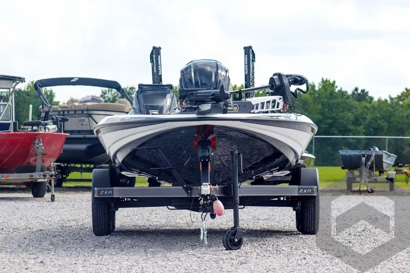 Slide: The Image of 2025 Skeeter ZXR 20 boat on trailer, parked on gravel, with other boats in background. - 2