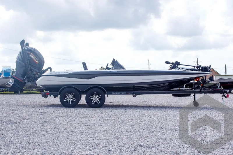 Slide: The Image of 2025 Skeeter ZXR 20 boat on trailer, parked on gravel, under cloudy sky. - 4