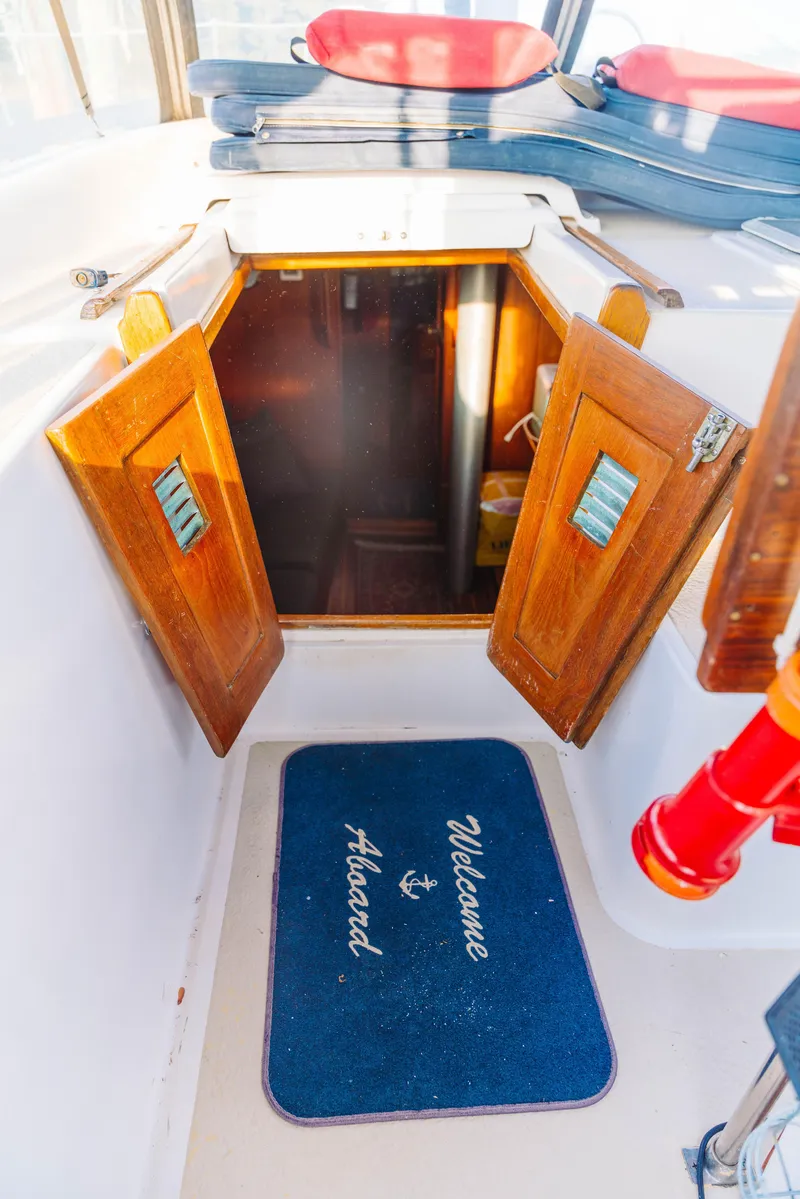 Slide: The Image of 1983 Morgan Out Island 41 yacht entrance with open wooden doors and "Welcome Aboard" mat. - 11