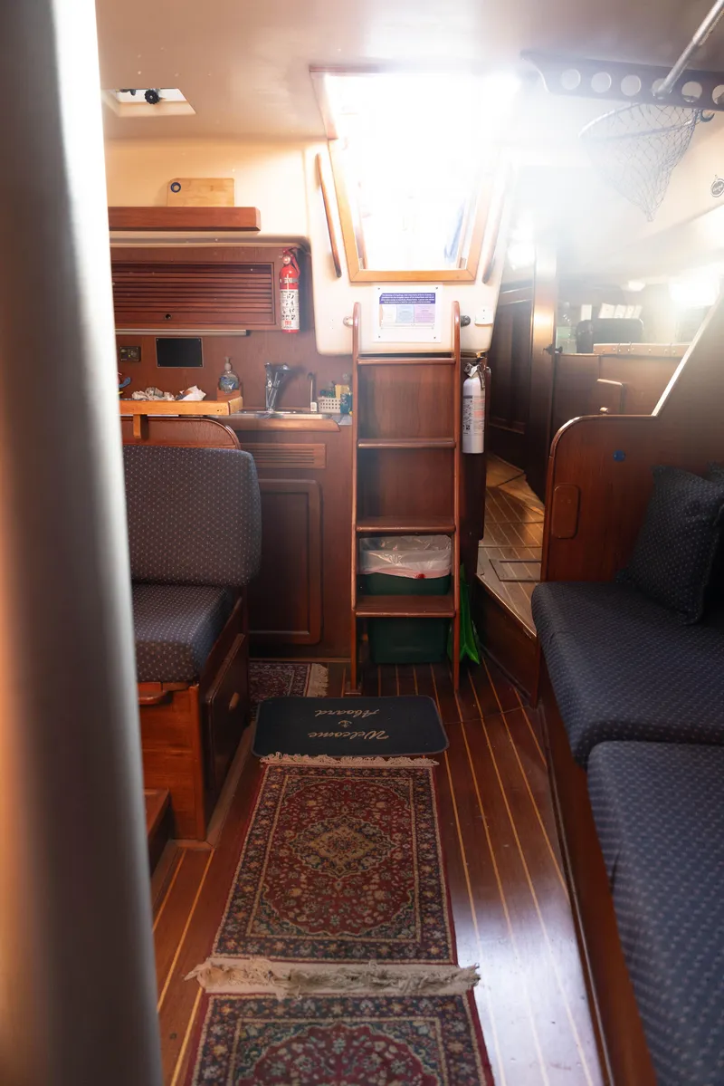 Slide: The Image of Interior of 1983 Morgan Out Island 41 sailboat, featuring cozy seating and wooden cabinetry. - 17