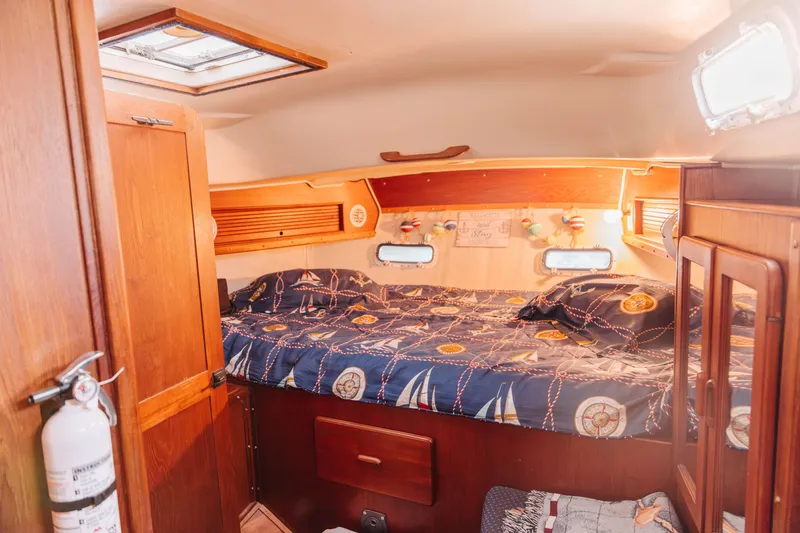 Slide: The Image of 1983 Morgan Out Island 41 yacht cabin with nautical-themed bedding and wooden interior. - 23