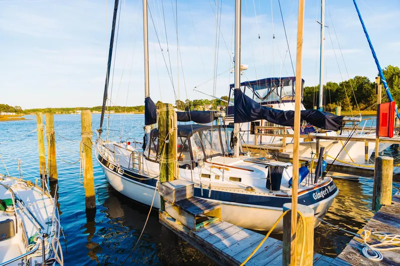Slide: The Image of 1983 Morgan Out Island 41 sailboat docked at a marina, surrounded by calm water. - 31