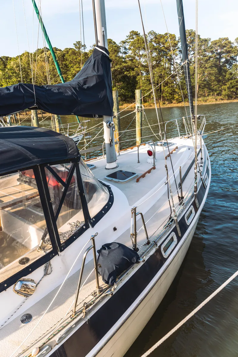 Slide: The Image of 1983 Morgan Out Island 41 sailboat docked on calm water, surrounded by trees. - 4