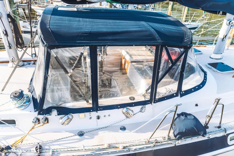 Slide: The Image of 1983 Morgan Out Island 41 sailboat with blue canopy and clear windows in marina. - 5