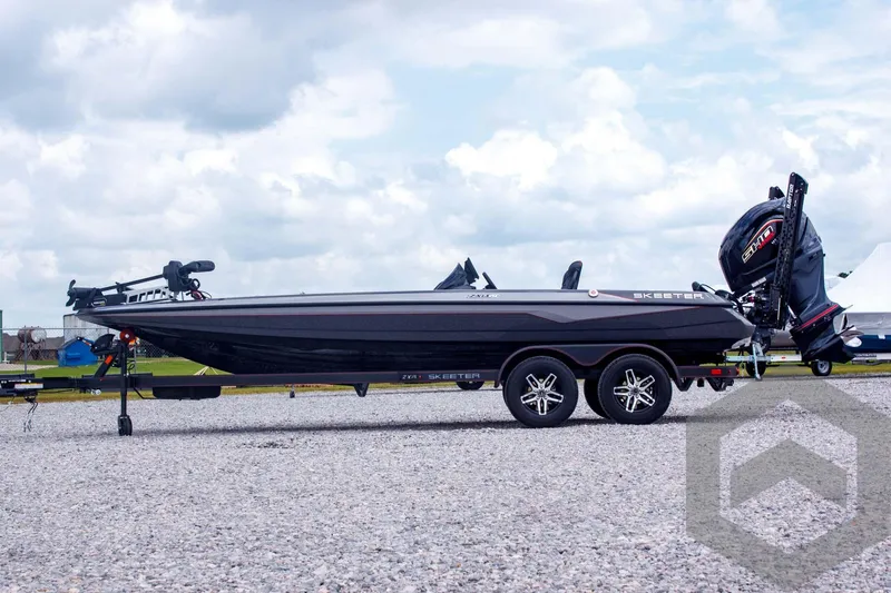 Slide: The Image of 2025 Skeeter ZXR 21 boat on trailer, parked on gravel under cloudy sky. - 8