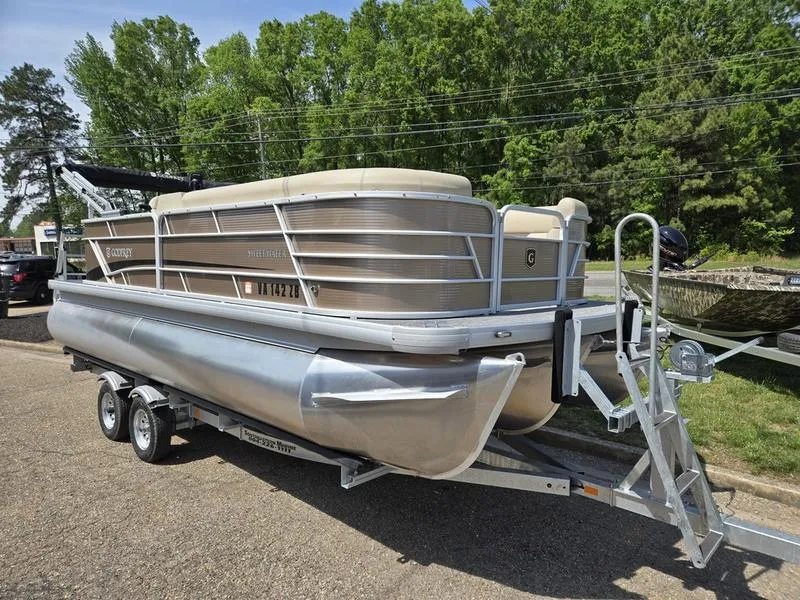 Slide: The Image of 2025 Godfrey Sweetwater 2186 C Sport Tube pontoon boat on trailer, parked outdoors. - 0