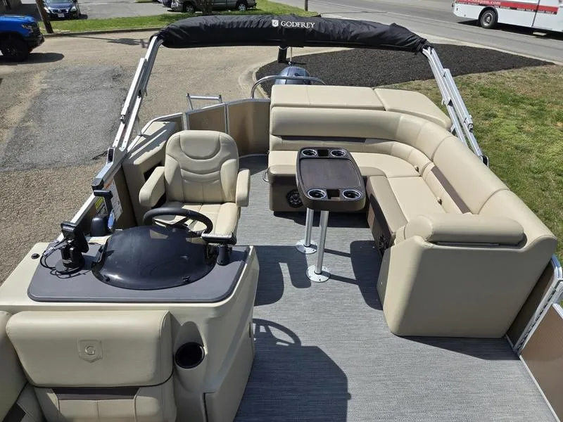 Slide: The Image of 2025 Godfrey Sweetwater 2186 C Sport Tube pontoon boat with beige seating and steering console. - 6