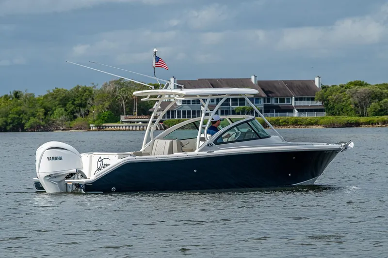 Slide: The Image of 2021 Pursuit DC 246 Dual Console boat on water, with American flag and Yamaha engine. - 11