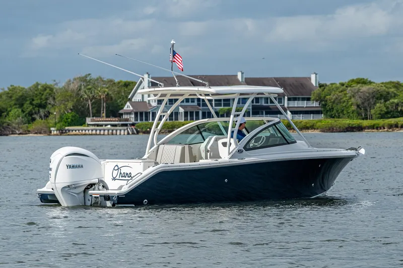 Slide: The Image of 2021 Pursuit DC 246 Dual Console boat on water with American flag and Yamaha engine. - 12