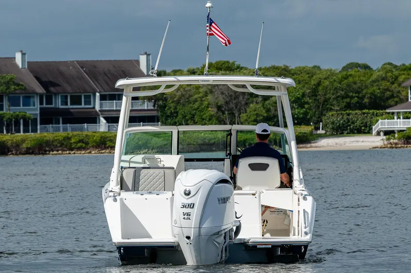 Slide: The Image of 2021 Pursuit DC 246 Dual Console boat on water, American flag, scenic background. - 13