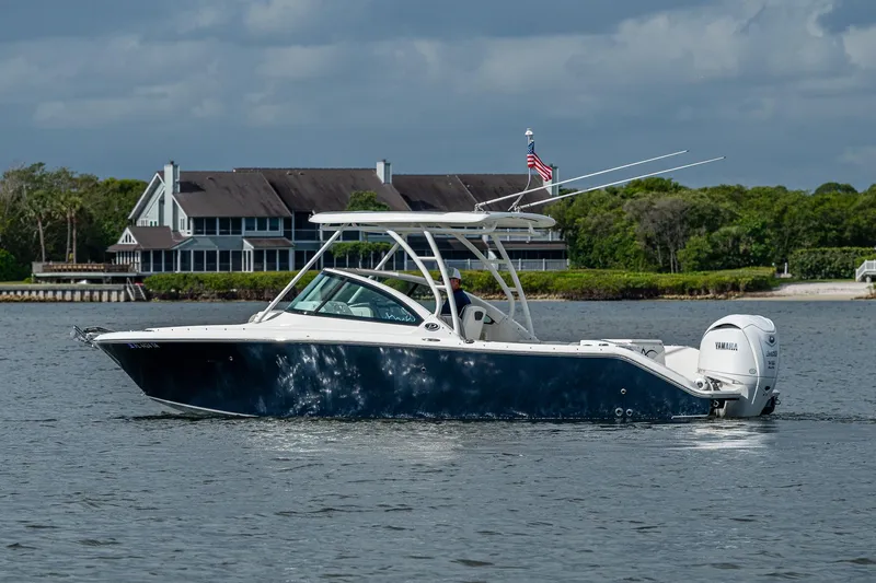 Slide: The Image of 2021 Pursuit DC 246 Dual Console boat cruising on a calm lake near a large house. - 15
