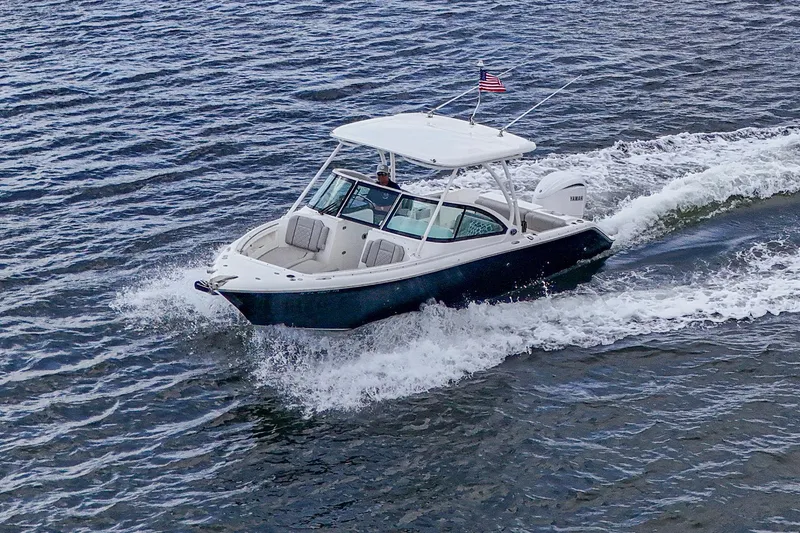 Slide: The Image of 2021 Pursuit DC 246 Dual Console boat cruising on open water with American flag. - 16