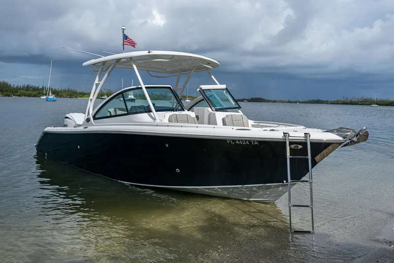 Slide: The Image of 2021 Pursuit DC 246 Dual Console boat anchored in shallow water, with an American flag. - 2