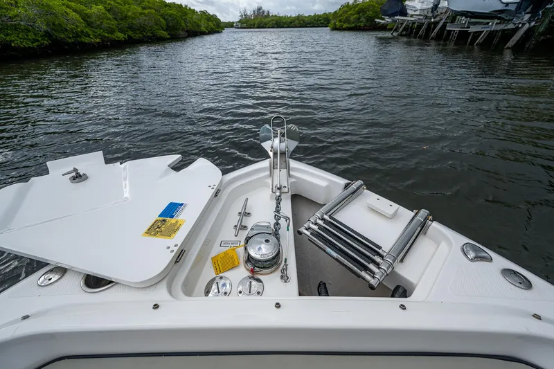 Slide: The Image of 2021 Pursuit DC 246 Dual Console boat on a calm river with lush greenery. - 23