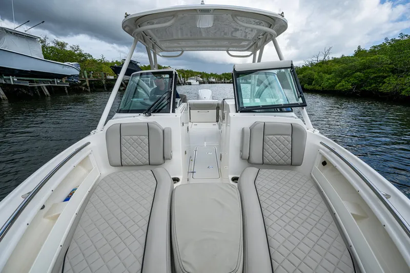 Slide: The Image of 2021 Pursuit DC 246 Dual Console boat interior with cushioned seating on a calm waterway. - 24