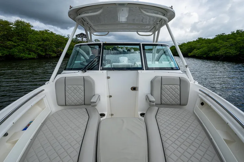 Slide: The Image of 2021 Pursuit DC 246 Dual Console boat with cushioned seating on a calm river. - 25