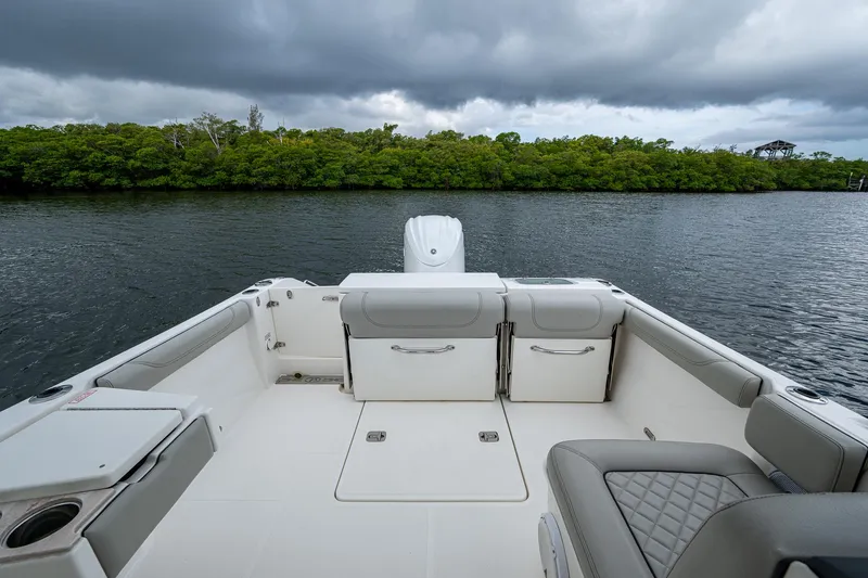 Slide: The Image of 2021 Pursuit DC 246 Dual Console boat interior with seating, on a calm waterway under cloudy skies. - 28