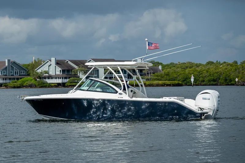 Slide: The Image of 2021 Pursuit DC 246 Dual Console boat on water, American flag, houses in background. - 3