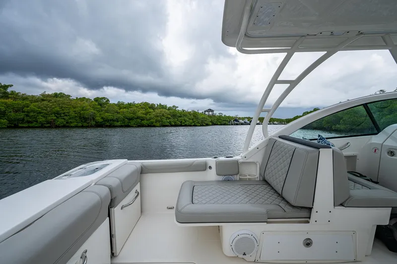 Slide: The Image of 2021 Pursuit DC 246 Dual Console boat interior with gray seating, on a calm river. - 30