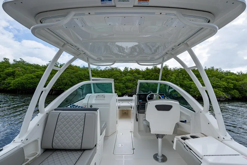 Slide: The Image of 2021 Pursuit DC 246 Dual Console boat interior with seating and helm, surrounded by lush greenery. - 32