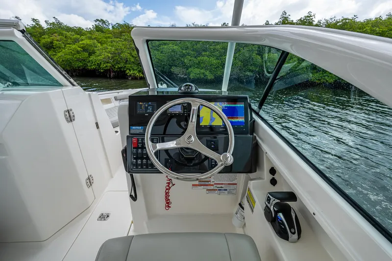 Slide: The Image of 2021 Pursuit DC 246 Dual Console boat cockpit with steering wheel and navigation system. - 37