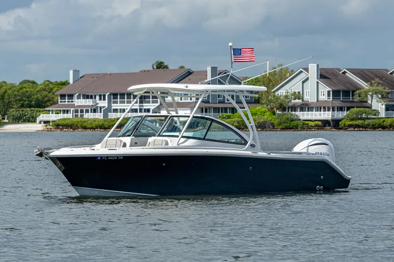 Slide: The Image of 2021 Pursuit DC 246 Dual Console boat on water, with houses and American flag in background. - 4