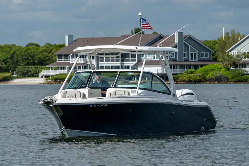 Slide: The Image of 2021 Pursuit DC 246 Dual Console boat cruising near waterfront homes. - 5