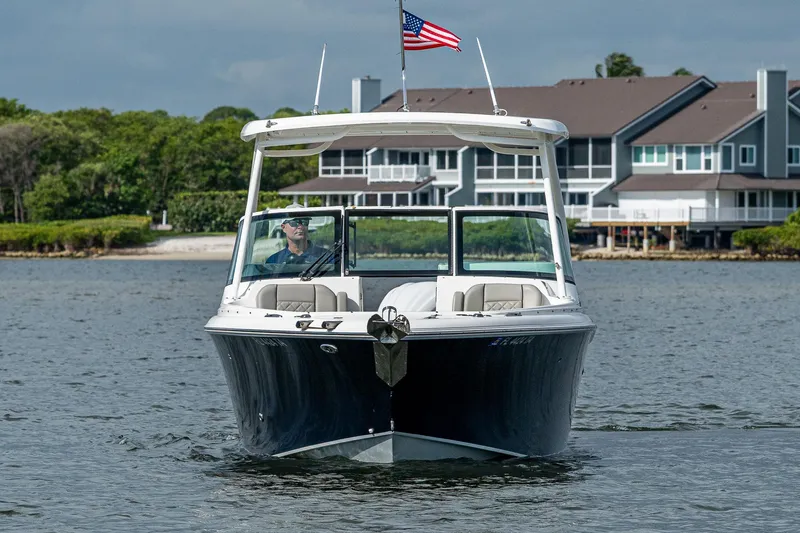 Slide: The Image of 2021 Pursuit DC 246 Dual Console boat on water, American flag, waterfront homes in background. - 6