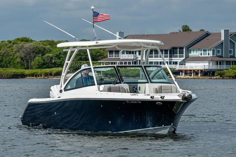 Slide: The Image of 2021 Pursuit DC 246 Dual Console boat cruising on a lake near waterfront homes. - 7