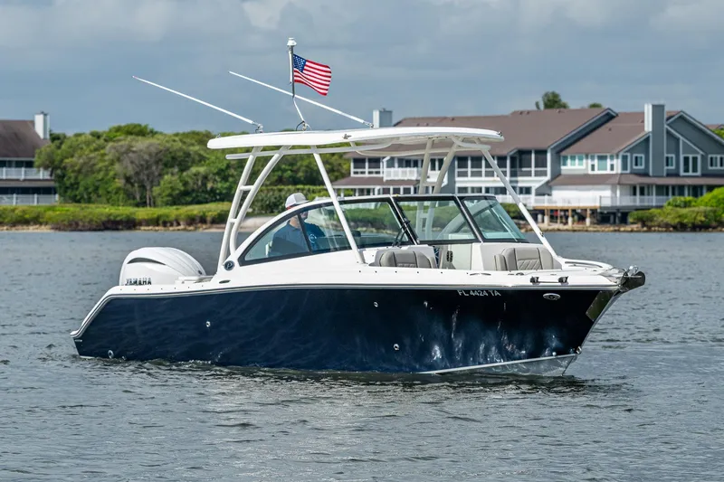 Slide: The Image of 2021 Pursuit DC 246 Dual Console boat on water, American flag, waterfront homes in background. - 8